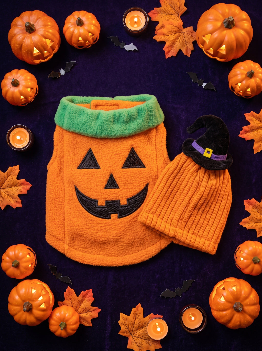 Pumpkin vest and hood flat lay with mini pumpkins, leaves and candles